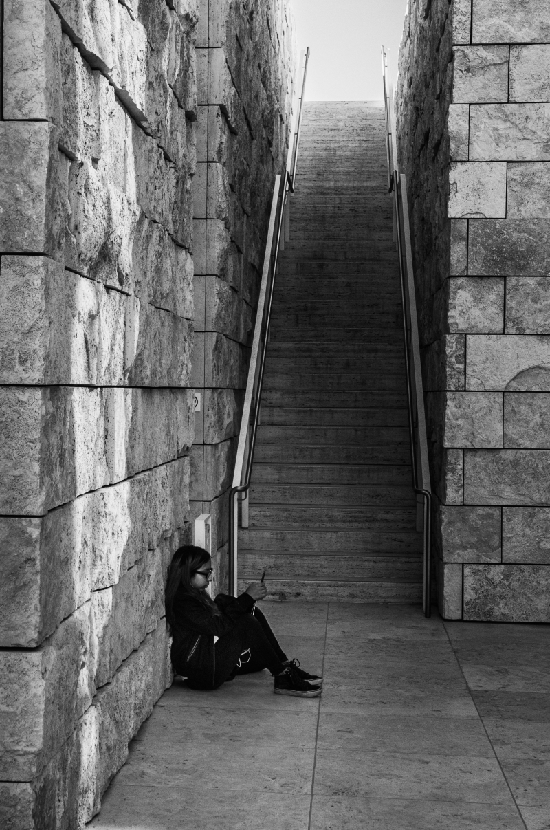 Jeune fille assise par terre au pied d'un grand escalier